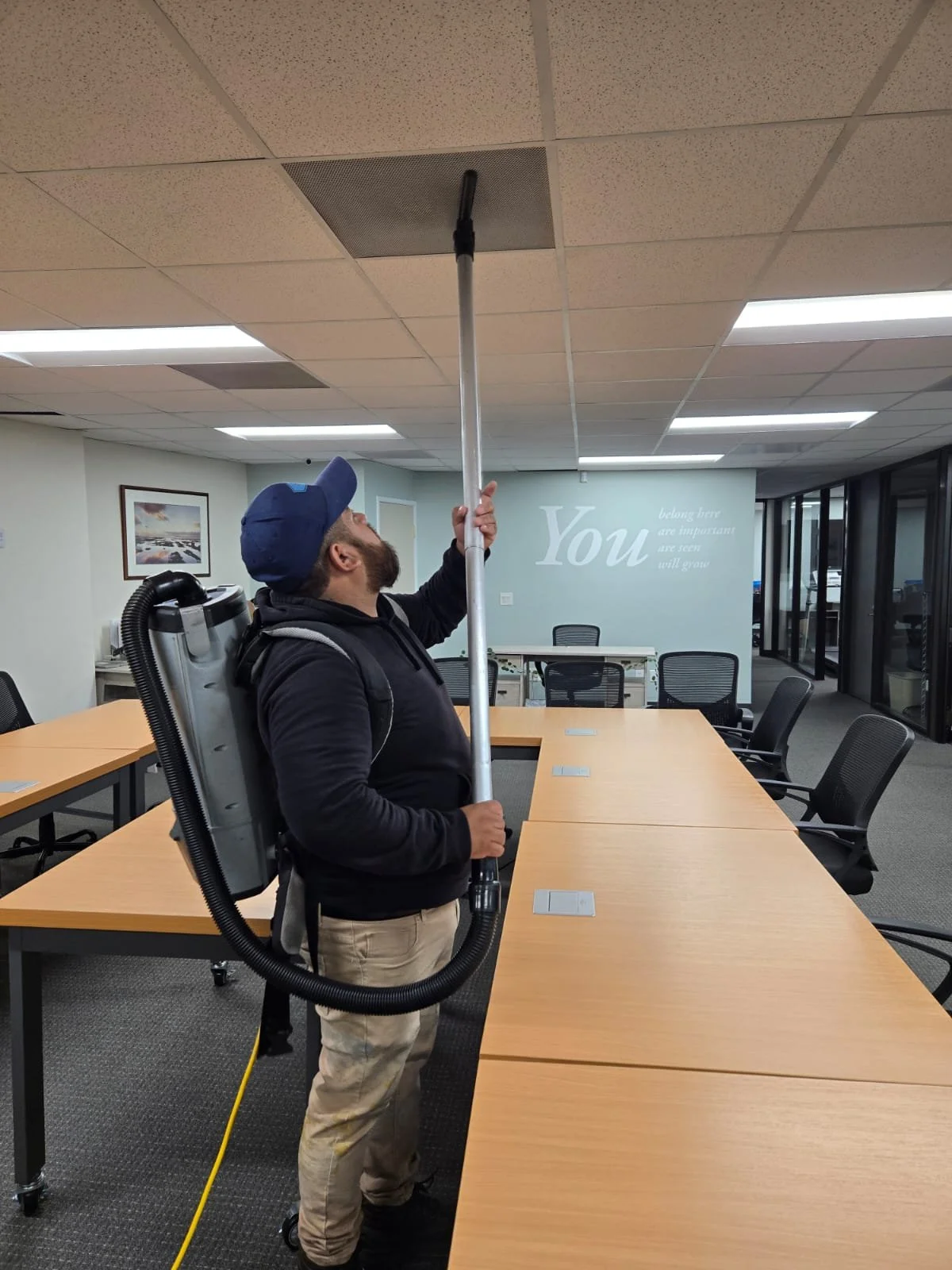 Oracle Group technician cleaning ceiling vents in a San Diego commercial office