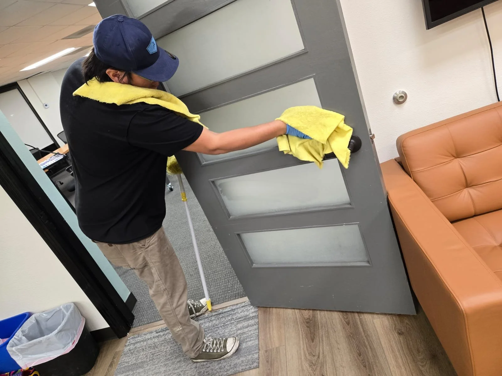 Technician disinfecting surfaces and doors in a commercial facility in San Diego